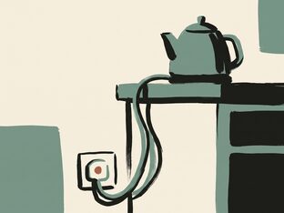 A kettle on a counter, its cord running down to a wall socket with a small ember glow