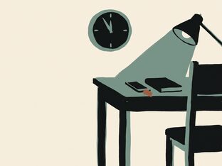 An empty desk at night, lamp on, clock reading late, phone face down
