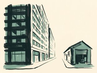 A tall office block and a small workshop facing each other across an empty street